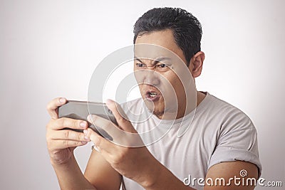 Funny Young Asian Guy Playing Games on Tablet Stock Photo