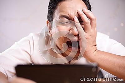 Funny Young Asian Guy Playing Games on Tablet Stock Photo