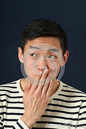 Funny young Asian man covering his mouth by palm Stock Photo