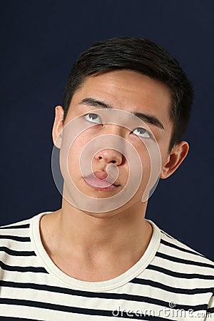 Funny young Asian man making face and rolling eyes up Stock Photo