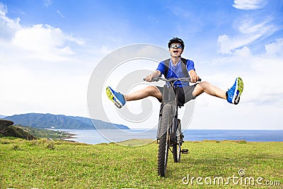 Funny young backpacker riding a bicycle on a meadow Stock Photo