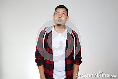 Funny young confused Asian man thinking expression, looking up contemplation gesture over white Stock Photo