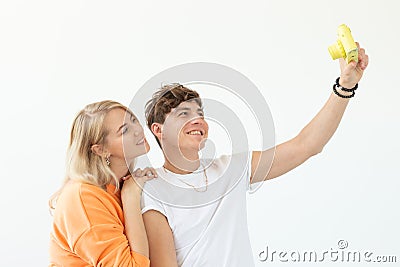 Funny young couple in love cute man and charming woman making selfie on vintage yellow film camera posing on a white Stock Photo