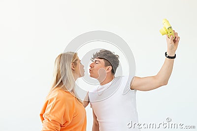 Funny young couple in love cute man and charming woman making selfie on vintage yellow film camera posing on a white Stock Photo