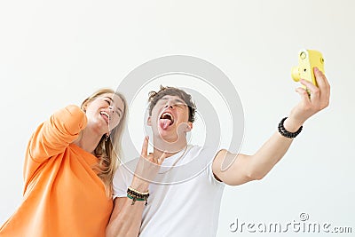 Funny young couple in love cute man and charming woman making selfie on vintage yellow film camera posing on a white Stock Photo