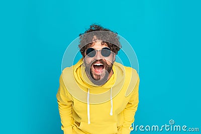 Funny young man in yellow hoodie opening mouth and laughing Stock Photo