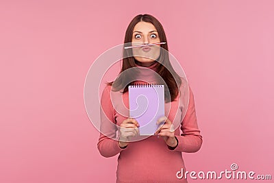 Funny young woman having fun holding pencil with lip and nose, female student resting during hometask doing Stock Photo