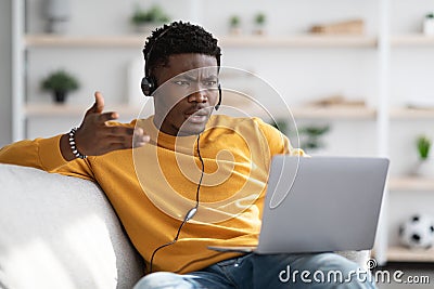 Furious black guy having video call, using laptop at home Stock Photo