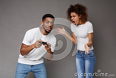 Furious black woman yelling at her boyfriend playing with joystick Stock Photo