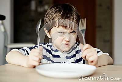 Furious little boy waiting for dinner Stock Photo