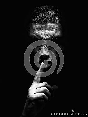 Furious mature man with an aggressive look making the silence sign in a violent and threatening way. Stock Photo