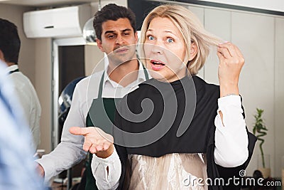 Furious mature woman screaming on hairdresser as hair cut badly Stock Photo