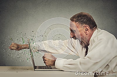 Furious senior businessman throws punch into computer Stock Photo