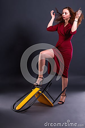 A furious woman knocks over chair, kicks him and gestures with her hands, tossing her hair Stock Photo