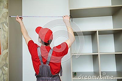 Furniture assembling. Professional worker measuring wardrobe aperture during installation at living room Stock Photo