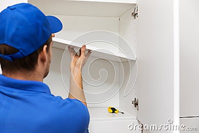 Furniture assembly - worker installing cabinet shelf Stock Photo