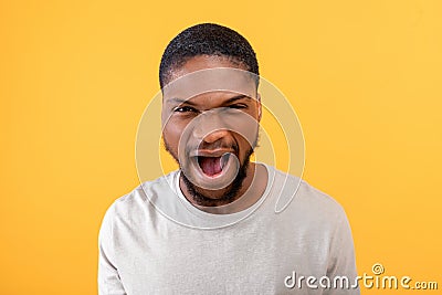 Fury. Angry black guy shouting emotionally at camera, expressing anger and aggression over yellow background Stock Photo