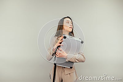 Fussy business woman with a suitcase of money in her hands stands on a beige background and looks away Stock Photo