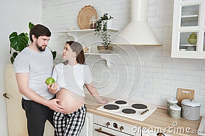 Future parents embrace standing in the kitchen Stock Photo