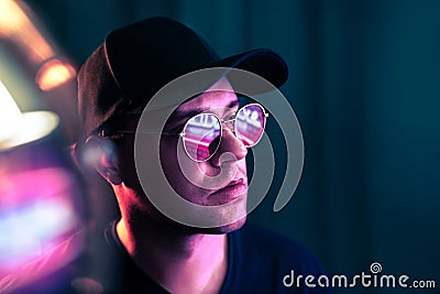 Futuristic neon technology. Man with glasses in future cyberpunk illumination. Purple fluorescent color on face. Studio portrait. Stock Photo