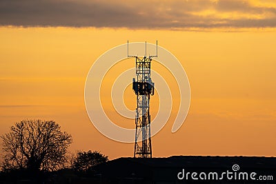 5G controversial radio mobile telephone broadcast transmitter mast silhouette at golden hour sunset. Summer sky with clouds Stock Photo