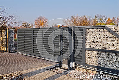 Gabion. Automatic entrance gate used in combination with a wall made of gabion Stock Photo