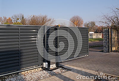 Gabion. Automatic entrance gate used in combination with a wall made of gabion Stock Photo