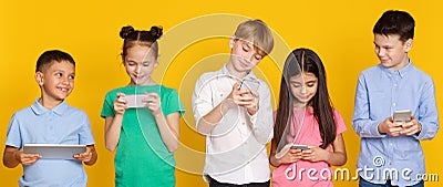 Gadget addiction. Children with modern gadgets, yellow background Stock Photo