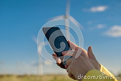 Gadget with a program for monitoring technical parameters in focus in human hands on a blurred background of wind turbines Stock Photo