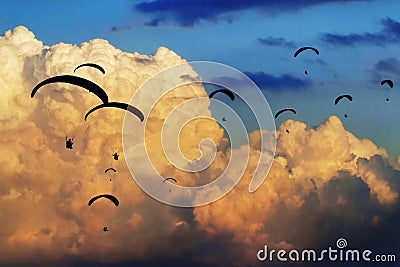 Gaggle of paragliders fly with giant clouds on the background Stock Photo