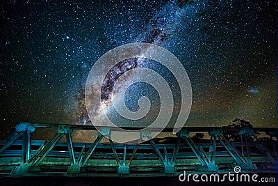 A galaxy of stars and the galactic core in the night sky over the steel road bridge Stock Photo