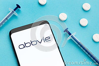 Smart phone showing Abbvie logo on screen and pills and syringe on blue background Editorial Stock Photo
