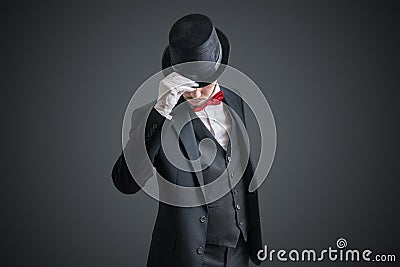 Gallant magician or illusionist in suit is taking off his hat Stock Photo