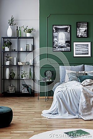 Gallery of black and white poster on green wall behind king size bed with pillows and blanket Stock Photo