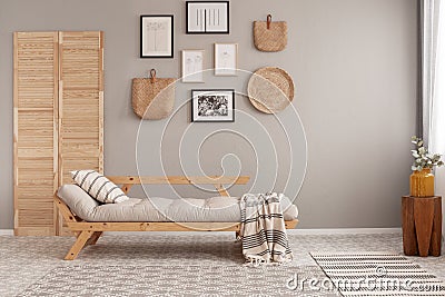 Posters in black frames and wicker kinck knack on beige wall of trendy living room interior with long settee with Stock Photo