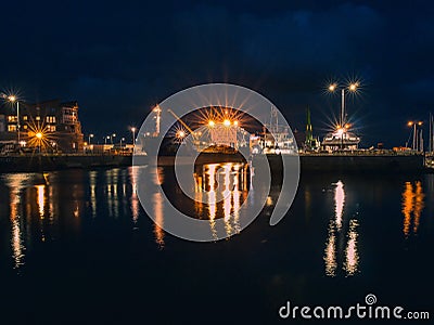 Galway - Ireland / 10/08/2020: Commercial ships in Galway Harbor illuminated at night. Reflection in the water. Night scene Editorial Stock Photo