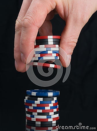 The gamblers hand, on a black background, adds game chips to the bet Stock Photo