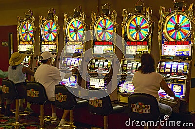 Gamblers putting coins into slot machines in Las Vegas, NV Editorial Stock Photo
