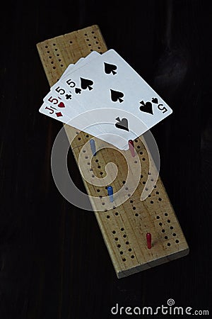 Playing cards and cribbage board on black background Stock Photo