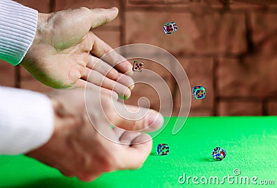 At the game table with a green cloth there is a game of craps. The player rolls the dice on the table surface Stock Photo