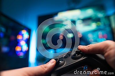 The gamer is playing a video game with friends. In his hands he has a modern joystick. Also in front is a large TV screen, Stock Photo