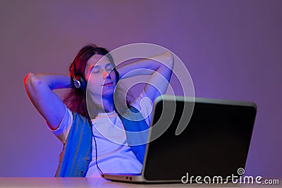Gamer or programmer at a laptop, portrait in neon light. Take a break from work, Stock Photo
