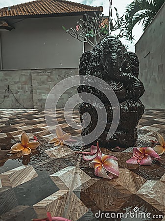 Ganesha statue dark stone color with fragipani flowers Stock Photo