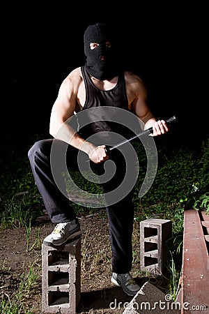 Gangster with baton outdoors at night Stock Photo