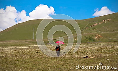 GANZI TIBETAN SICHUAN CHINA -AUGUST-19-2016 :Tibetan monkLama with red umbrella walking on the green hill and meditation Editorial Stock Photo