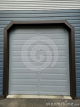 Garage door Grey color with dark blue metal siding with silver trim Stock Photo