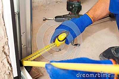 Garage doors installation. Worker use ruller to mesure the distance to metallic profile. Stock Photo