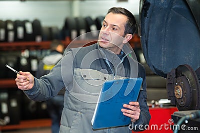 garage mechanic by car with wheel dismantled Stock Photo