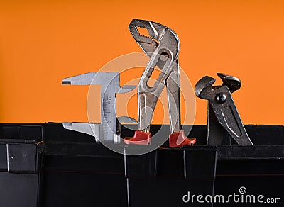 Garage plastic tool box with working tools isolated on an orange. Nippers, wrench, caliper. Stock Photo