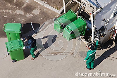 Garbage collection workers in residential area operating garbage truck Stock Photo